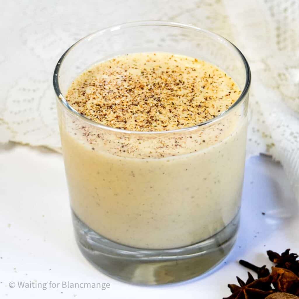 Glass of easy homemade eggnog topped with fresh grated nutmeg.
