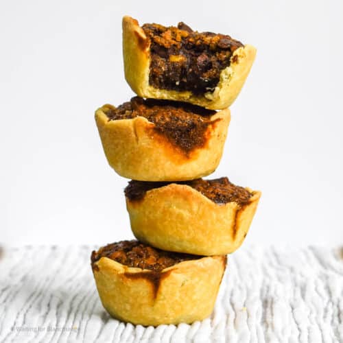 Stack of mini bourbon pecan pies with chocolate and coconut.