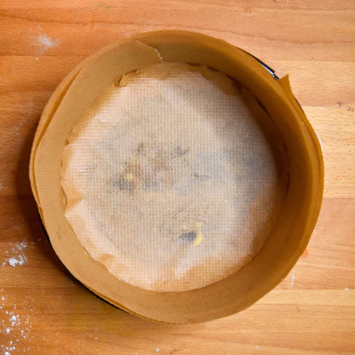 Overhead shot of a round cake pan lined with parchment paper.