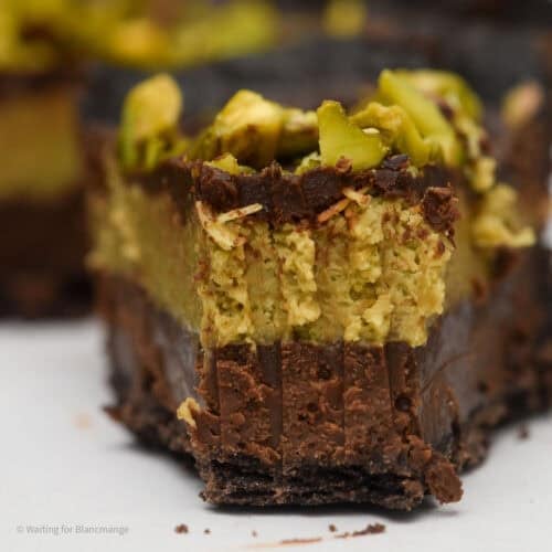 Close up image of a slice of Dubai chocolate tart showing the layers of chocolate base, pistachio kataifi filling and ganache topping.