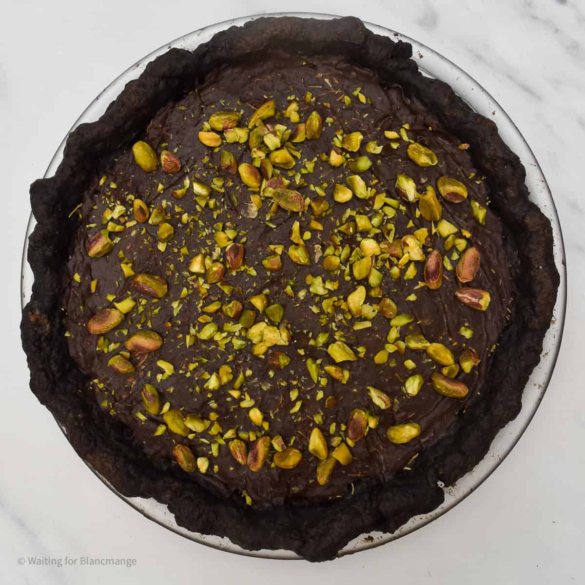 Overhead shot of a Dubai-style chocolate pistachio tart in a glass pie plate.
